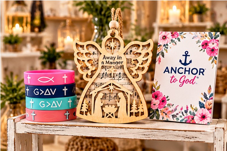 An angel-shaped nativity ornament with stacked wristbands and an Anchor to God card on a display shelf.